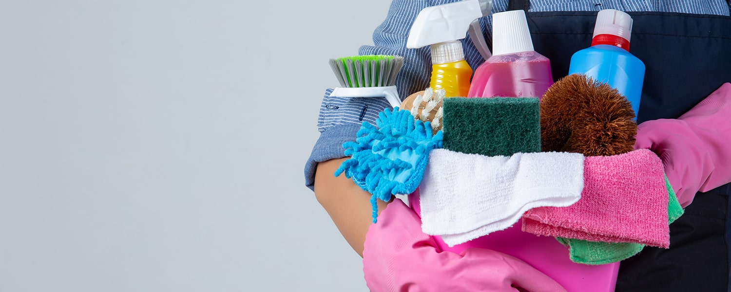 mujer-sostiene-productos-limpieza-guantes-trapos-cuenca-pared-blanca-min